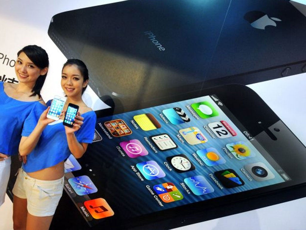 Two models display the Apple iPhone 5 during the product's release at a store in Taipei