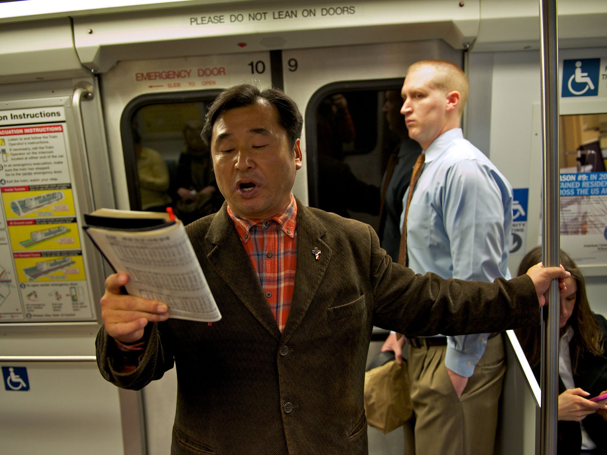 CAROLER: Fisher Yang, 50, sings a Christmas carol on a Metro train during a recent morning rush hour. He has performed on Metrorail since 1998.