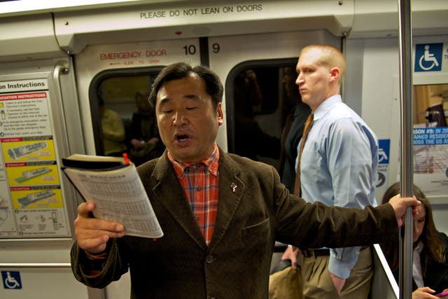 CAROLER: Fisher Yang, 50, sings a Christmas carol on a Metro train during a recent morning rush hour. He has performed on Metrorail since 1998. 