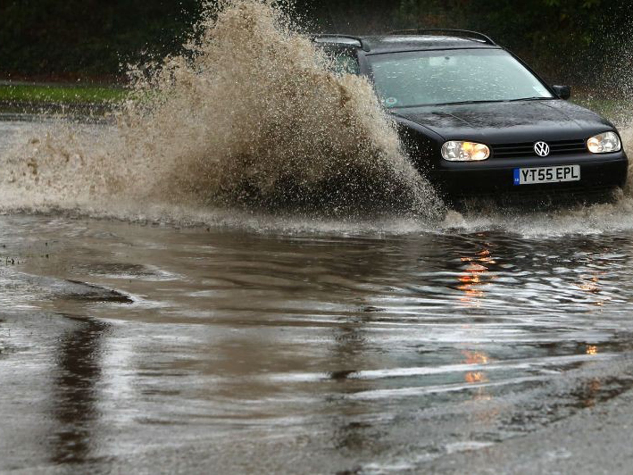 A motorist drives his car through flood waters in Chichester, West Sussex