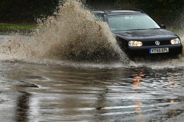 A motorist drives his car through flood waters in Chichester, West Sussex