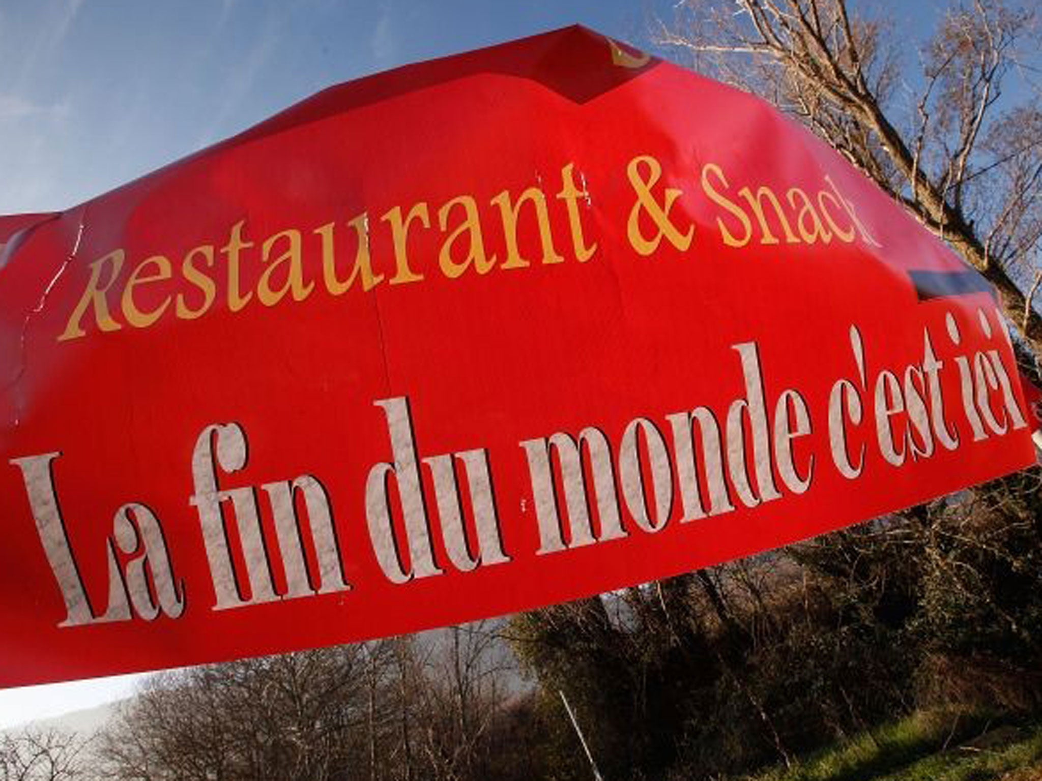 A sign, reading 'The end of the world, is here', advertises a restaurant in Bugarath, France, the small village said to be the only place on Earth which will be saved from this evening's apocalypse