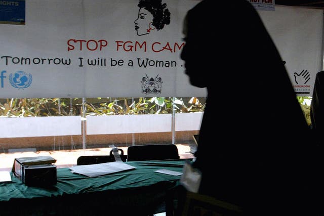 A young woman walks past a campaign banner against female genital mutilation [FGM] at the venue of an International conference, 16 September 2004 in Nairobi. 