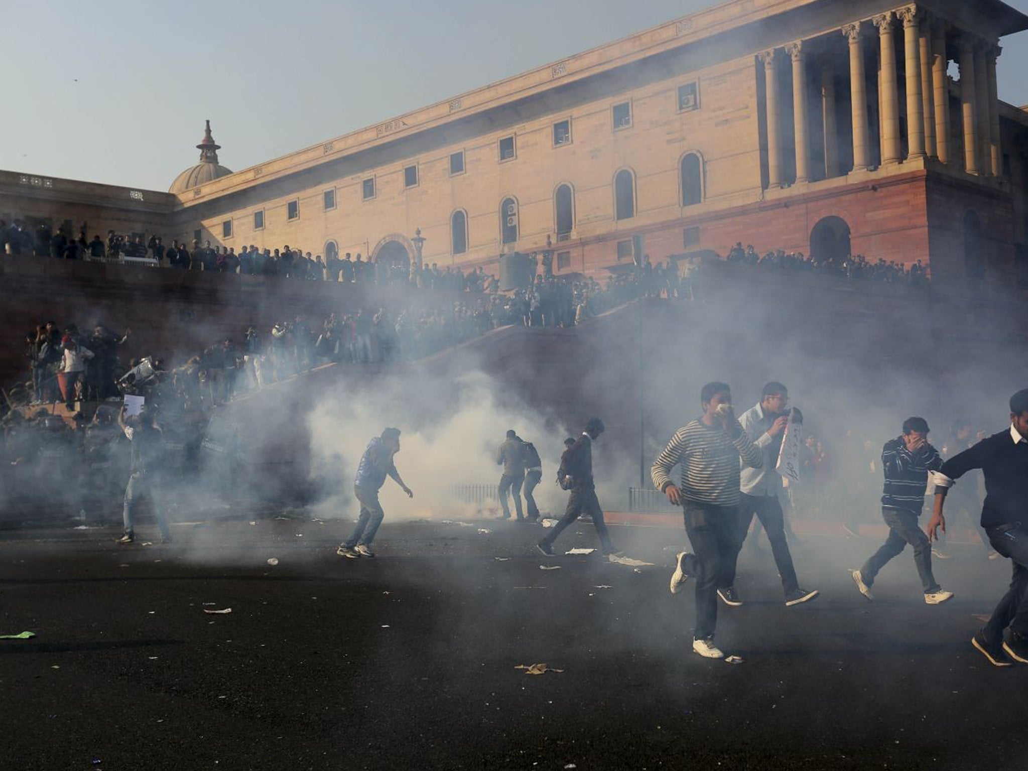 Protesters run from tear gas at the presidential palace in New Delhi