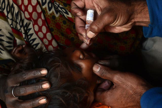 A Pakistani health worker gives polio vaccine drops to a young child last week