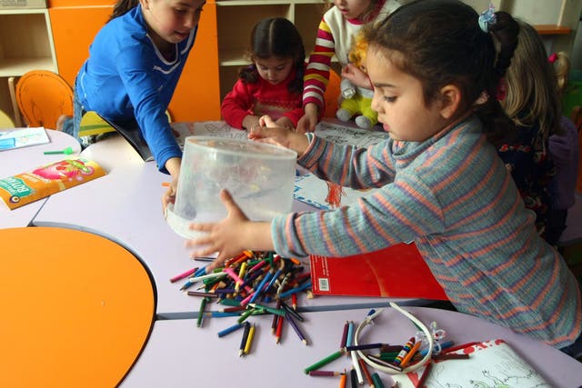 Syrian refugee children colour-in pages during a class at the refugee camp in Yayladagi 
