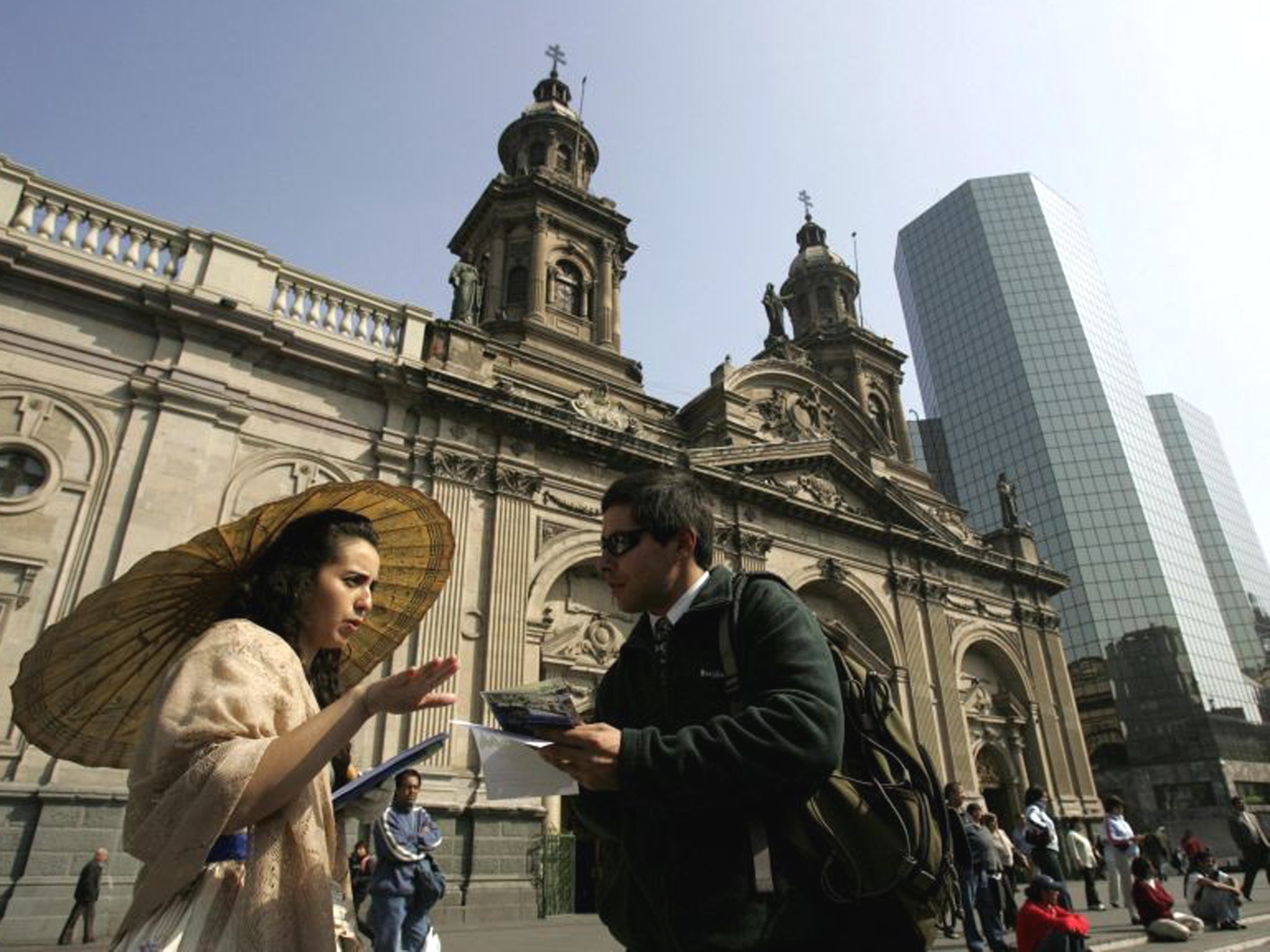 People speak in front of the Cathedral in the Plaza de Armas in Santiago