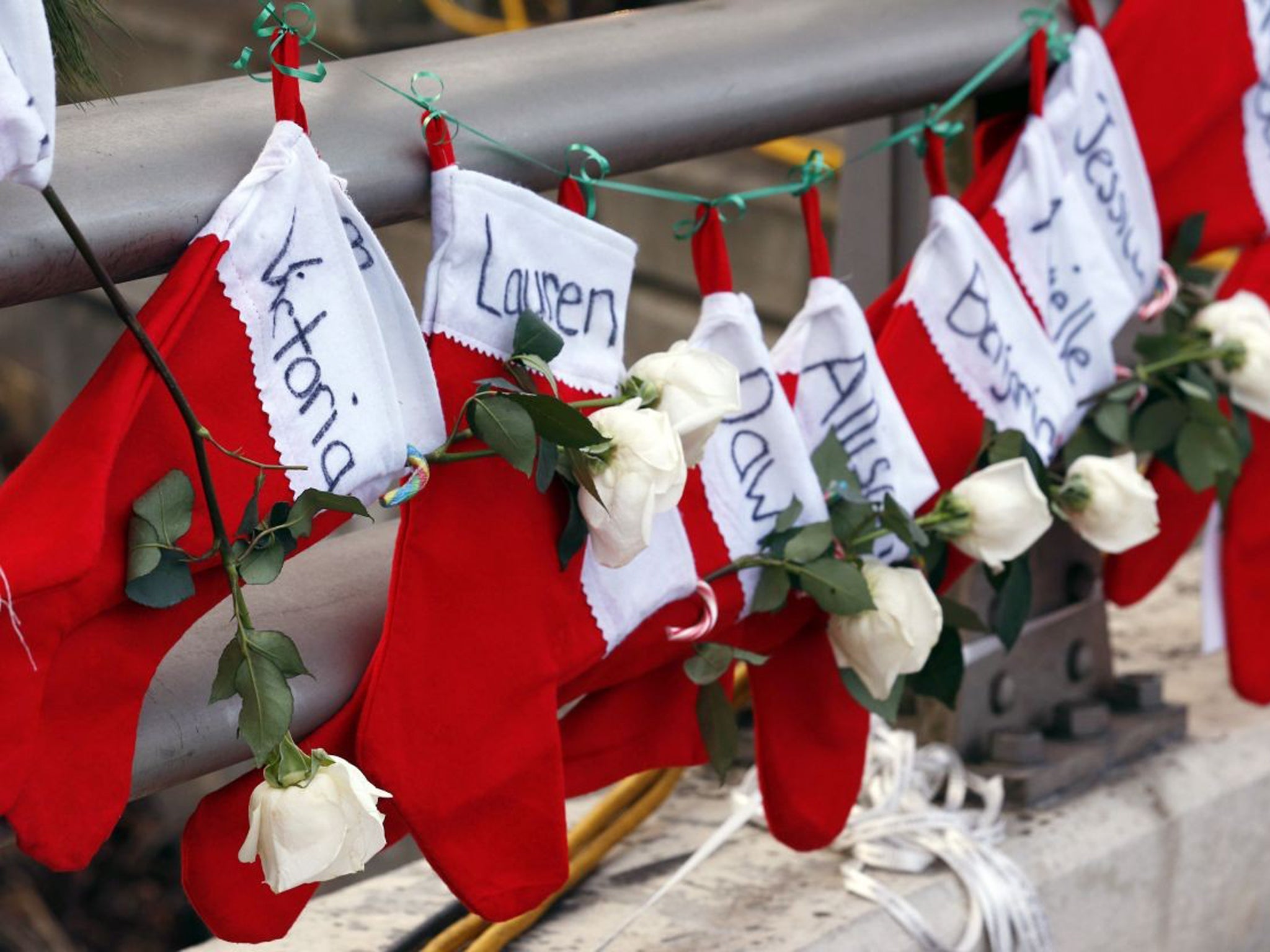 Christmas stockings with the names of shooting victims hang from railing near a makeshift memorial near the town Christmas tree in the Sandy Hook village of Newtown