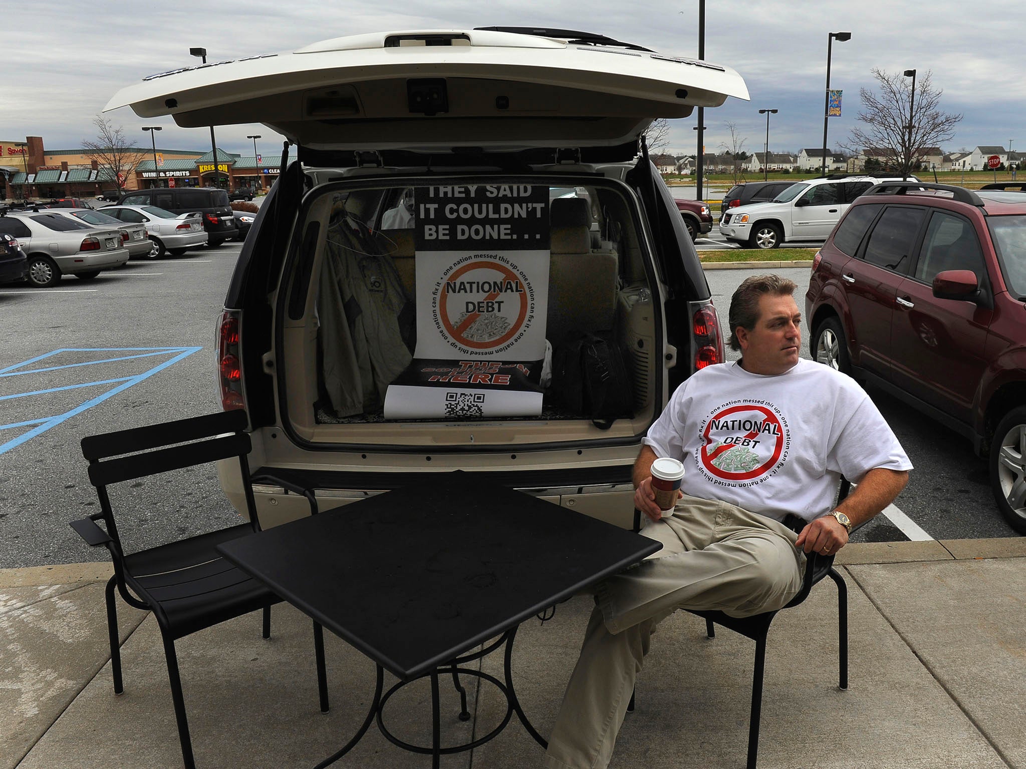 Scott Soucy sits in front of a Starbucks in Middletown, Del., waiting to engage people. His usual opening line is: "Hi there, do you want to talk about the national debt?" Most are skeptical of his plan.