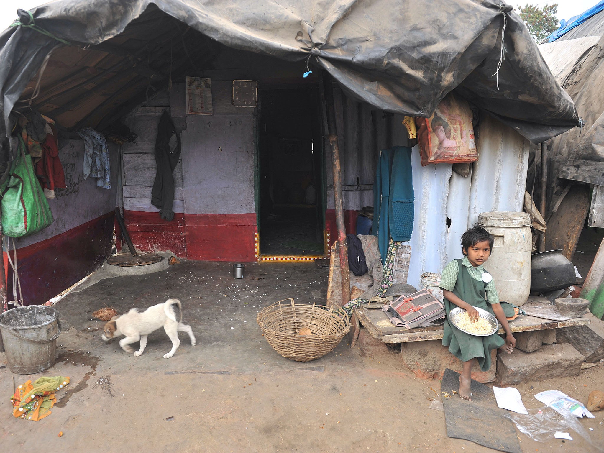 An Indian girl eats outside her home in a slum in Hyderabad