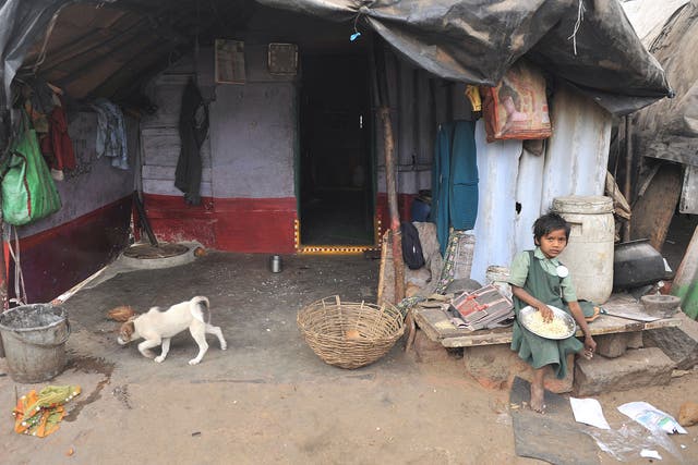 An Indian girl eats outside her home in a slum in Hyderabad