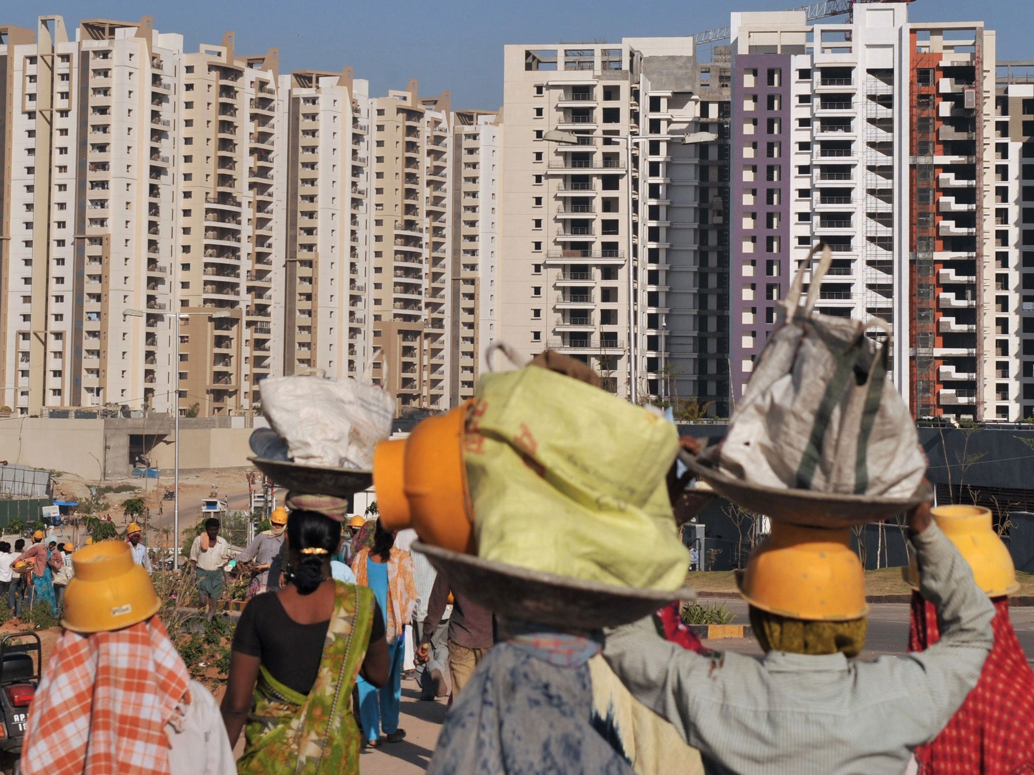 Indian labourers walk towards the residential apartments of IT employees at HITECH City or Cyberabad, in Hyderabad on March 3, 2012.