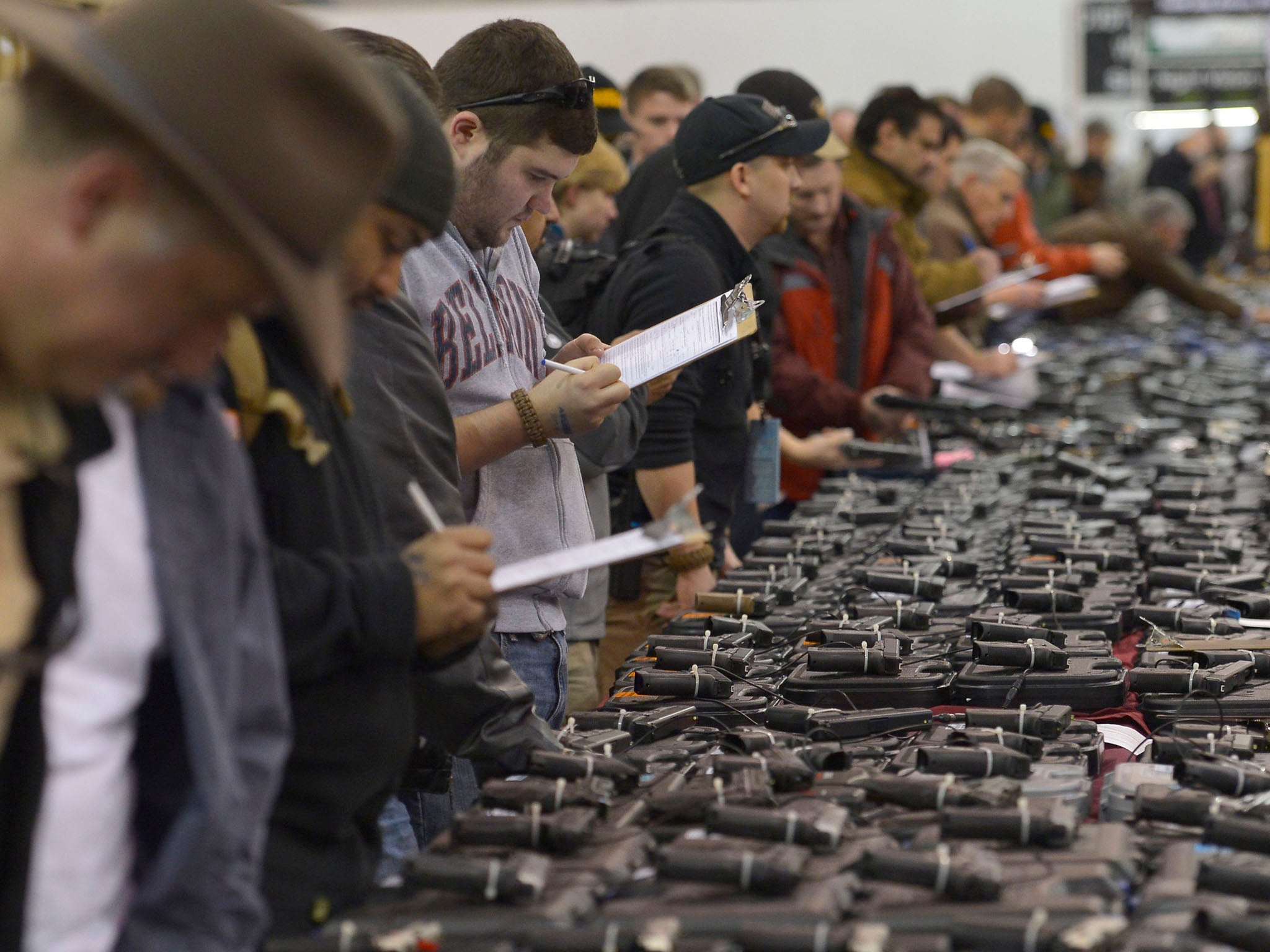 Gun enthusiasts fill out their background check paperwork while shopping for handguns at the Nation's Gun Show at the Dulles Expo Center in Chantilly, Virginia.