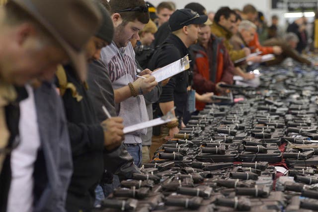Gun enthusiasts fill out their background check paperwork while shopping for handguns at the Nation's Gun Show at the Dulles Expo Center in Chantilly, Virginia. 