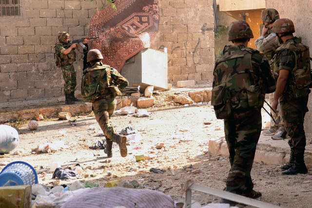 A Syrian army soldier runs across the street as others open fire during clashes with opposition fighters in the Tal al-Zarazi neighbourhood of the northern Syrian city of Aleppo on November 13, 2012. 