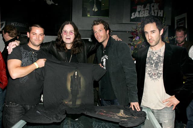 Black Sabbath holding up a T-shirt