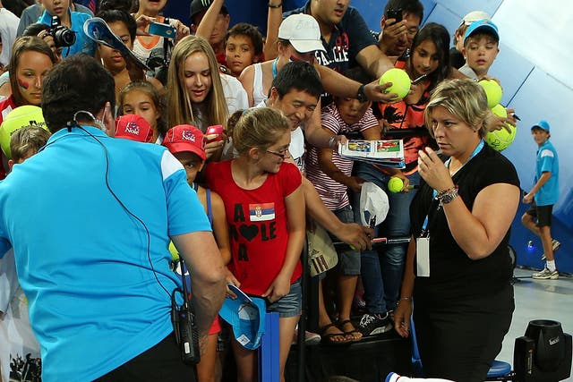 An advert hoarding gives way as spectators surge to get an autograph from Novak Djokovic
