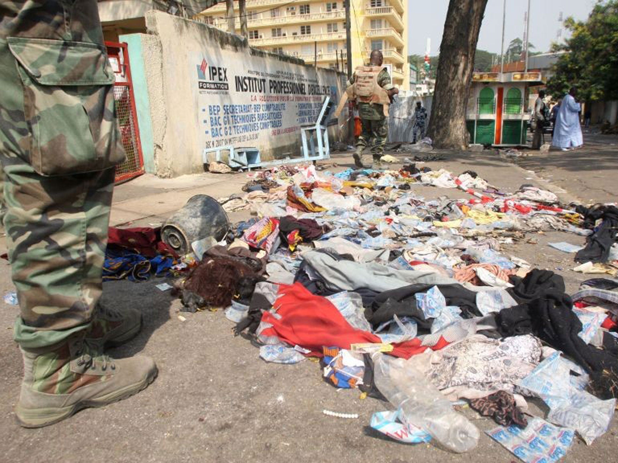 People stand next to clothing and various items spread over the pavement at the scene following a stampede in Abidjan
