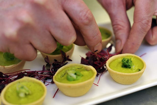 A royal chef adds the finishing garnish to a platter of Wilted Spring Onion and Water Cress quiche canapes, on March 25, 2011 in London, England