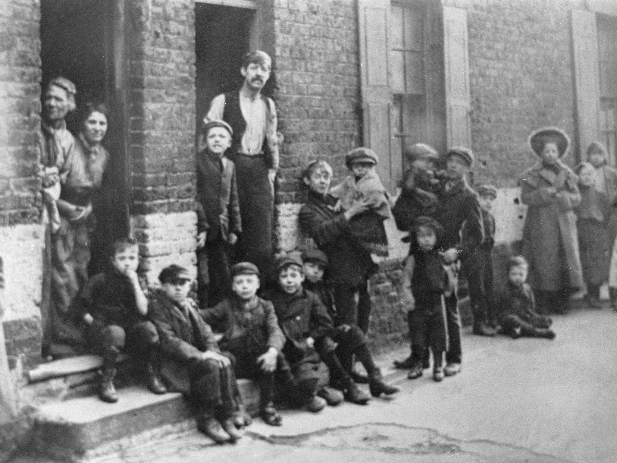 circa 1900: A group of boys and their families living in the East End of London.