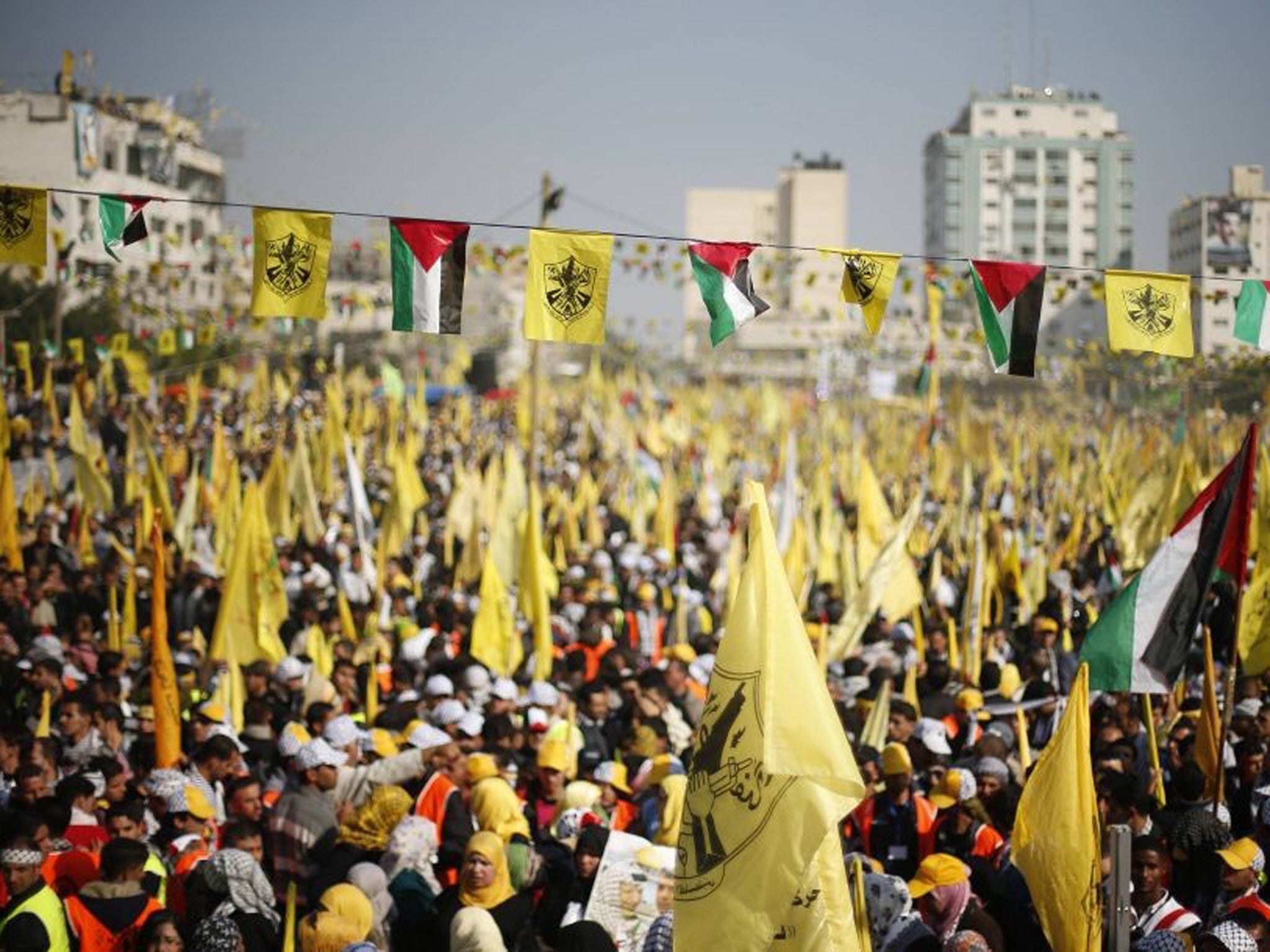 Fatah supporters wave the yellow flag of the party alongside the Palestinian flag