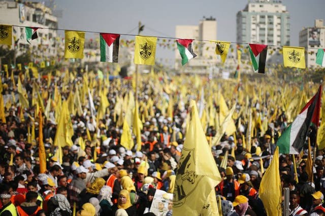 Fatah supporters wave the yellow flag of the party alongside the Palestinian flag