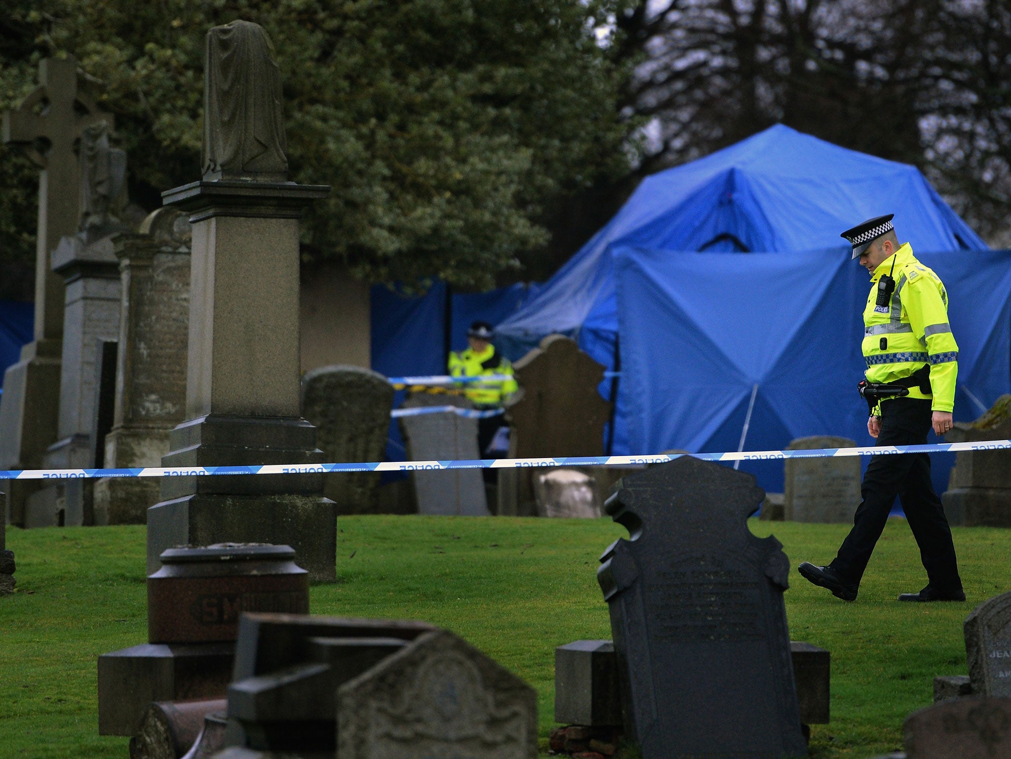 Police officers patrol Monkland Cemetery as forensic officers start examining a burial plot