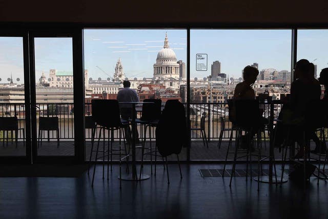Members of the public sit in a cafe on an upper floor of the Tate Modern gallery overlooking the River Thames and St Paul's Cathedral