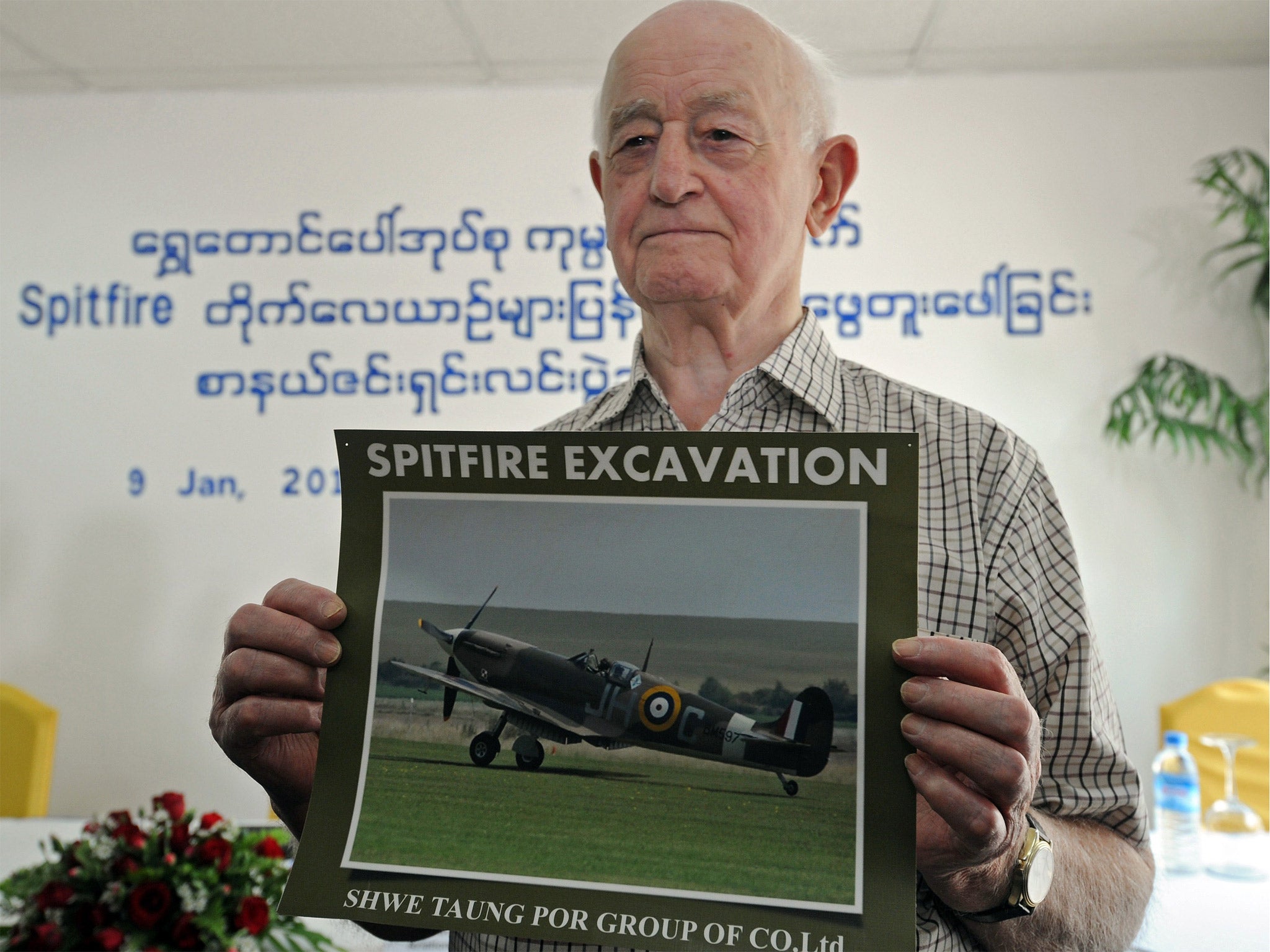 Stanley Coombe, a 91-year-old former British soldier, poses with a photo of a Spitfire