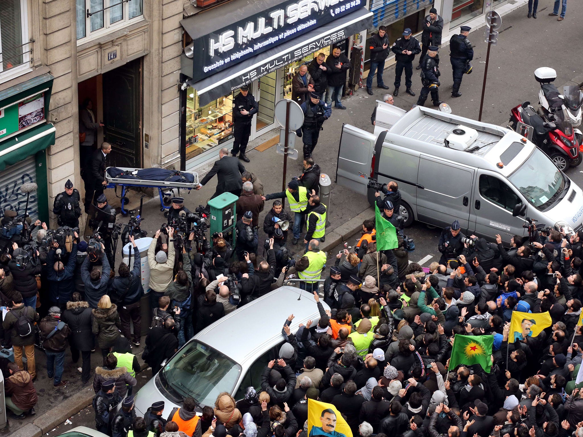 Police hold back crowds waving Kurdish flags as a body is removed from the office close to Gare du Nord yesterday