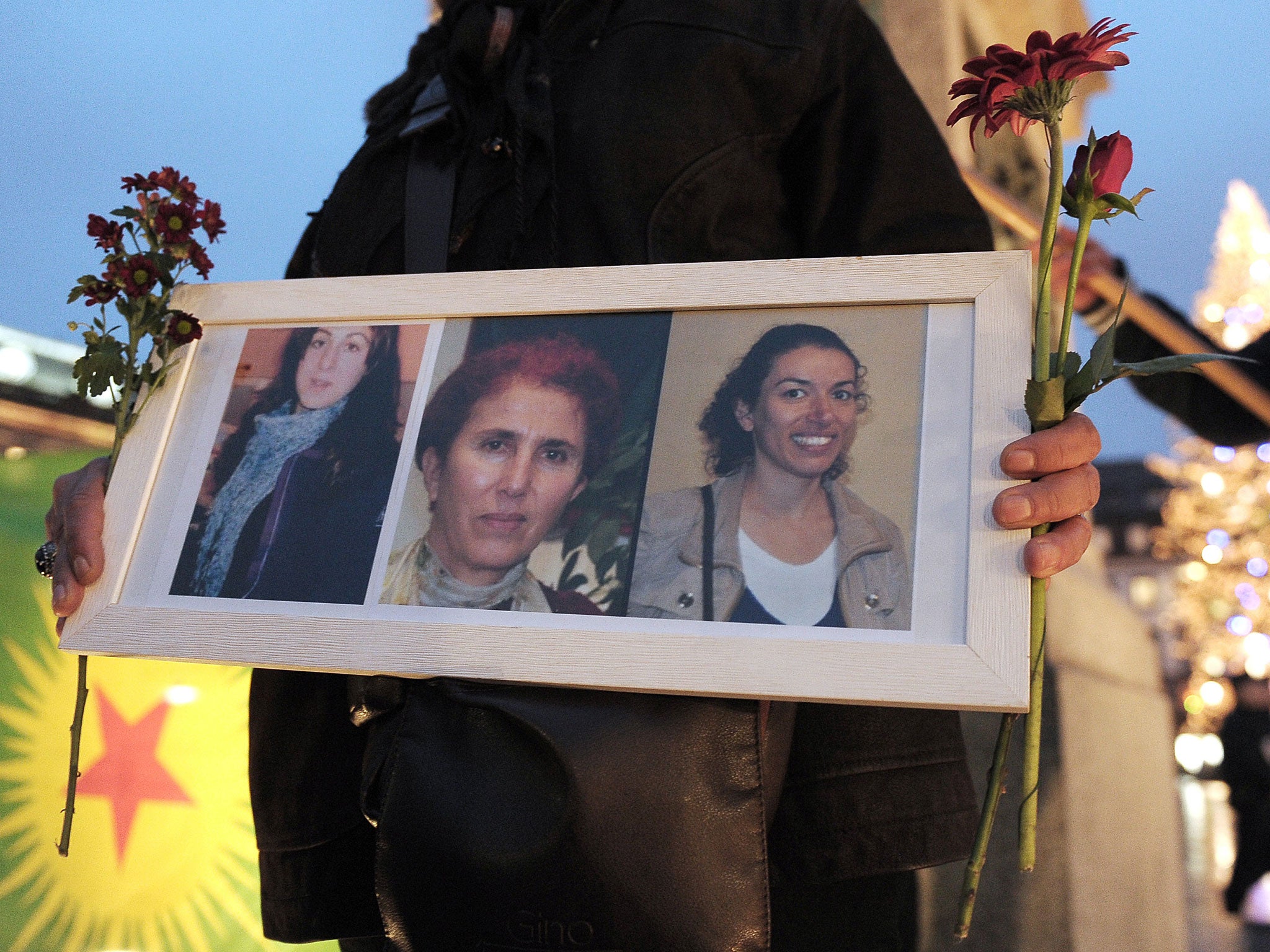 A woman holds a frame with photos of three Kurdish women activists, Sakine Cansiz, Fidan Dogan, Leyla Soylemez, killed in Paris