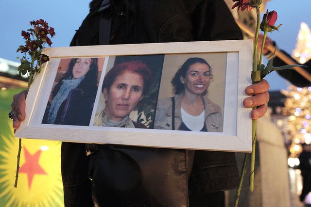 A woman holds a frame with photos of three Kurdish women activists, Sakine Cansiz, Fidan Dogan, Leyla Soylemez, killed  in Paris