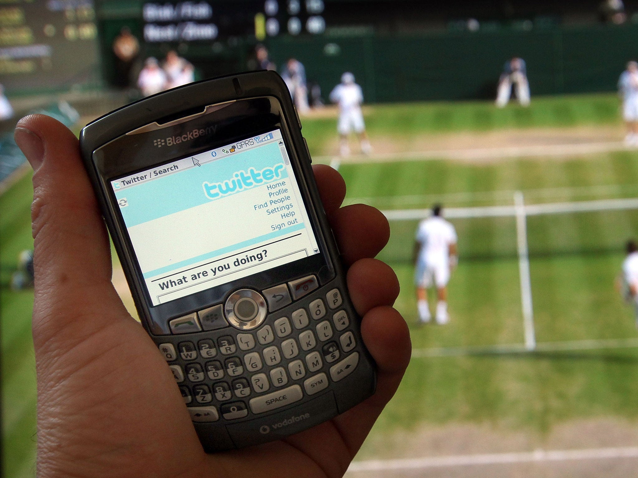 Twitter is displayed on a mobile phone in front of a television showing the tennis at Wimbledon on July 2, 2009 in London.