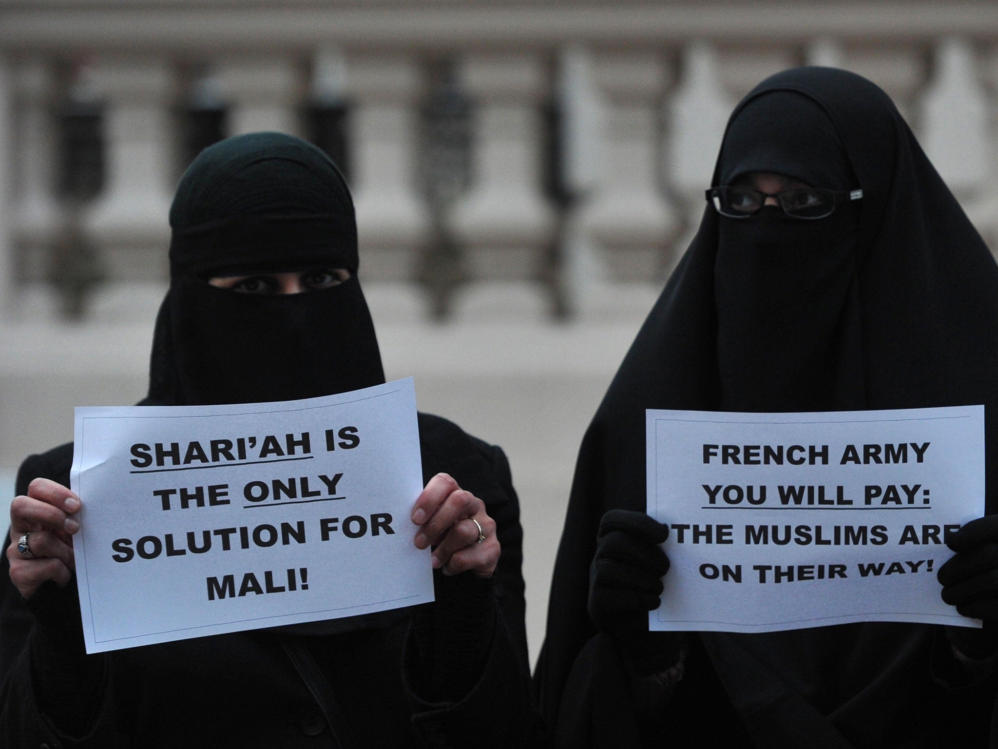Veiled Muslim women hold up signs as they join a protest in response to French military action in Mali outside the French embassy in central London on January 12, 2013.