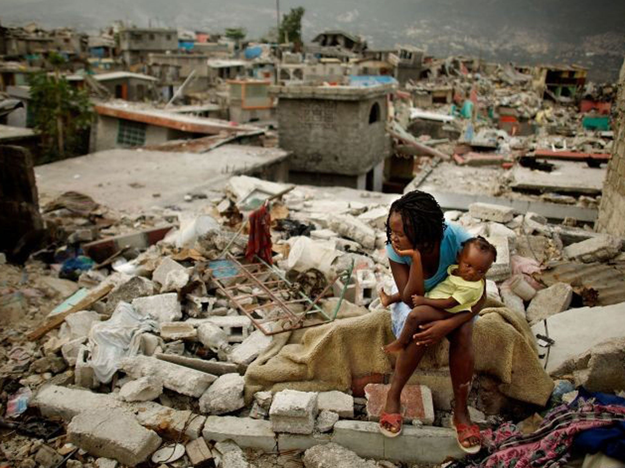 Sherider Anilus, 28, and her daughter, 9-month-old Monica, sit on the spot where her home collapsed during the earthquake in Port-au-Prince in Febuary 2010