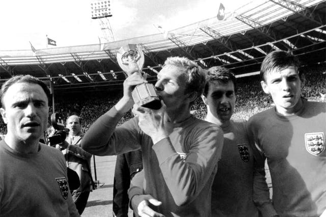 George Cohen (left) looks on as England captain Bobby Moore kisses the Jules Rimet trophy in 1966