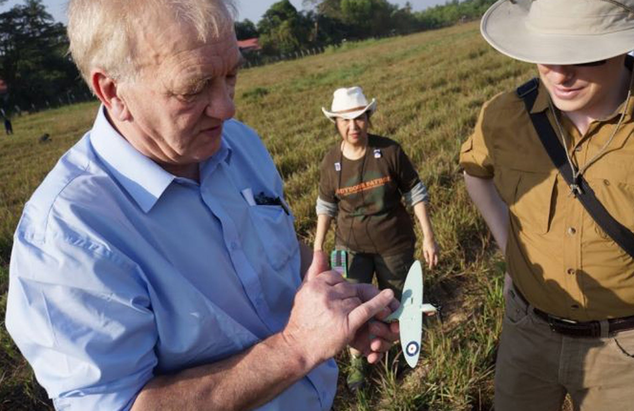 David Cundell holds a model Spitfire as he inspects a field in Burma earlier this month