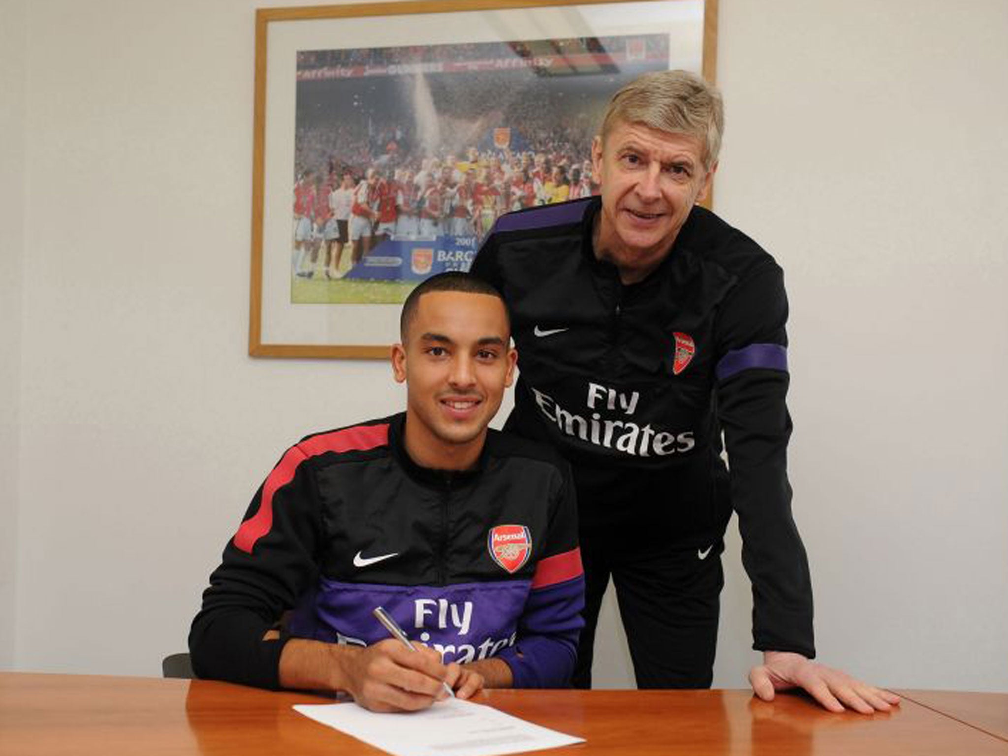 Theo Walcott signs his new deal watched by Arsène Wenger