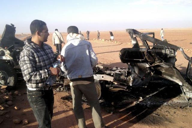 Men look at the wreckage of a vehicle near Ain Amenas, Algeria
