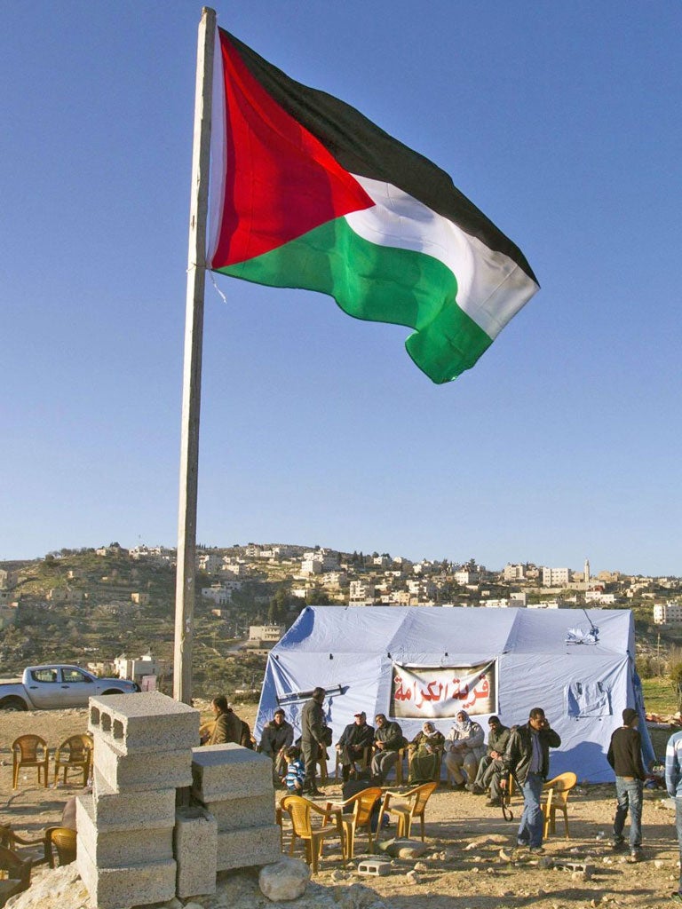 Palestinians pray in front of a tent at their makeshift settlement in Beit Iksa