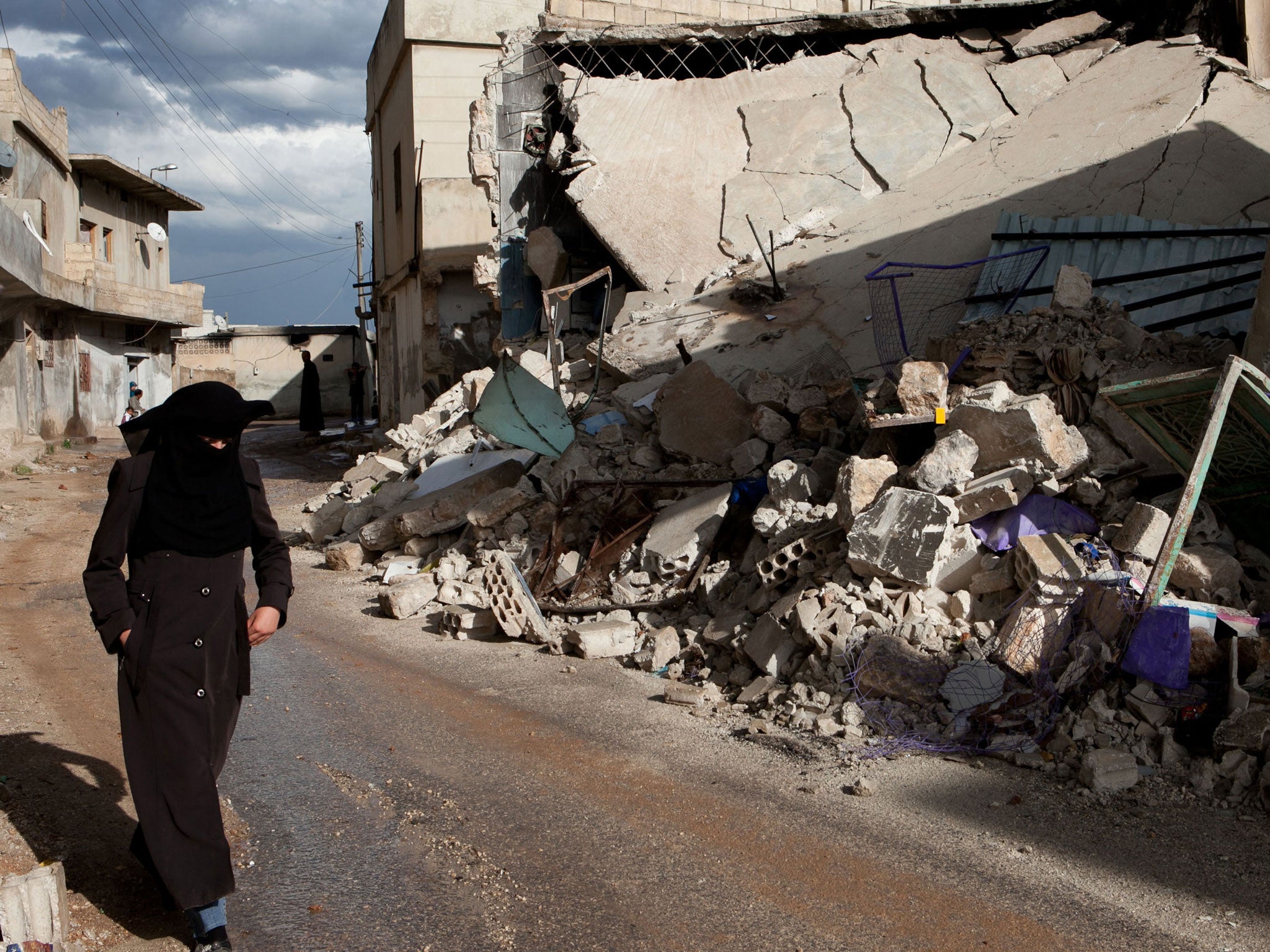 A Syrian woman walks past the rubble of homes allegedly destroyed during Syrian government army shelling in the town of Taftnaz, in northwestern Syria, on April 15, 2012.
