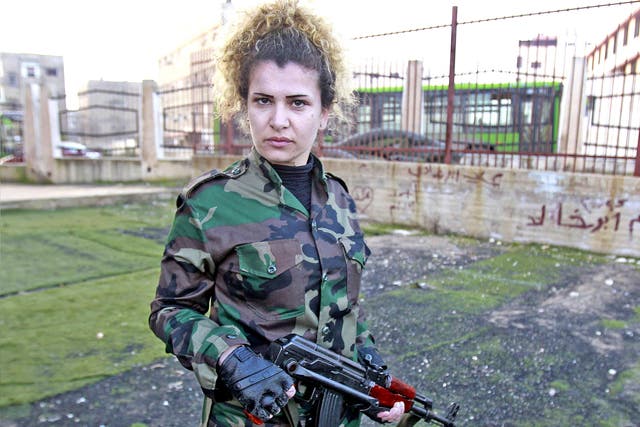 A Syrian National Defense force woman who just finished training, holds a rifle at the training center in Wadi al-Dahab