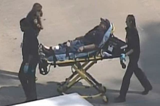 Police and emergency personnel evacuate an injured male on a stretcher outside a building on the Lone Star College Campus