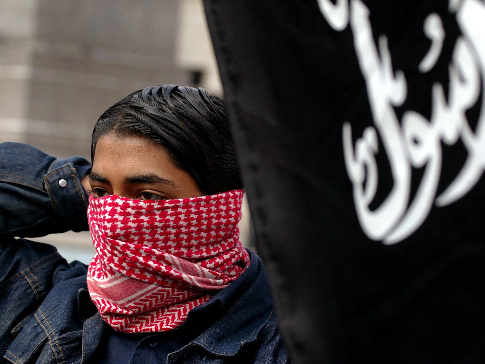 A boy ties on a scarf to hide his face August 25, 2002 during a 'Rally For Islam' demonstration held by Al-Muhajiroun, a UK-based Muslim pressure group in London, led by Anjem Choudary.