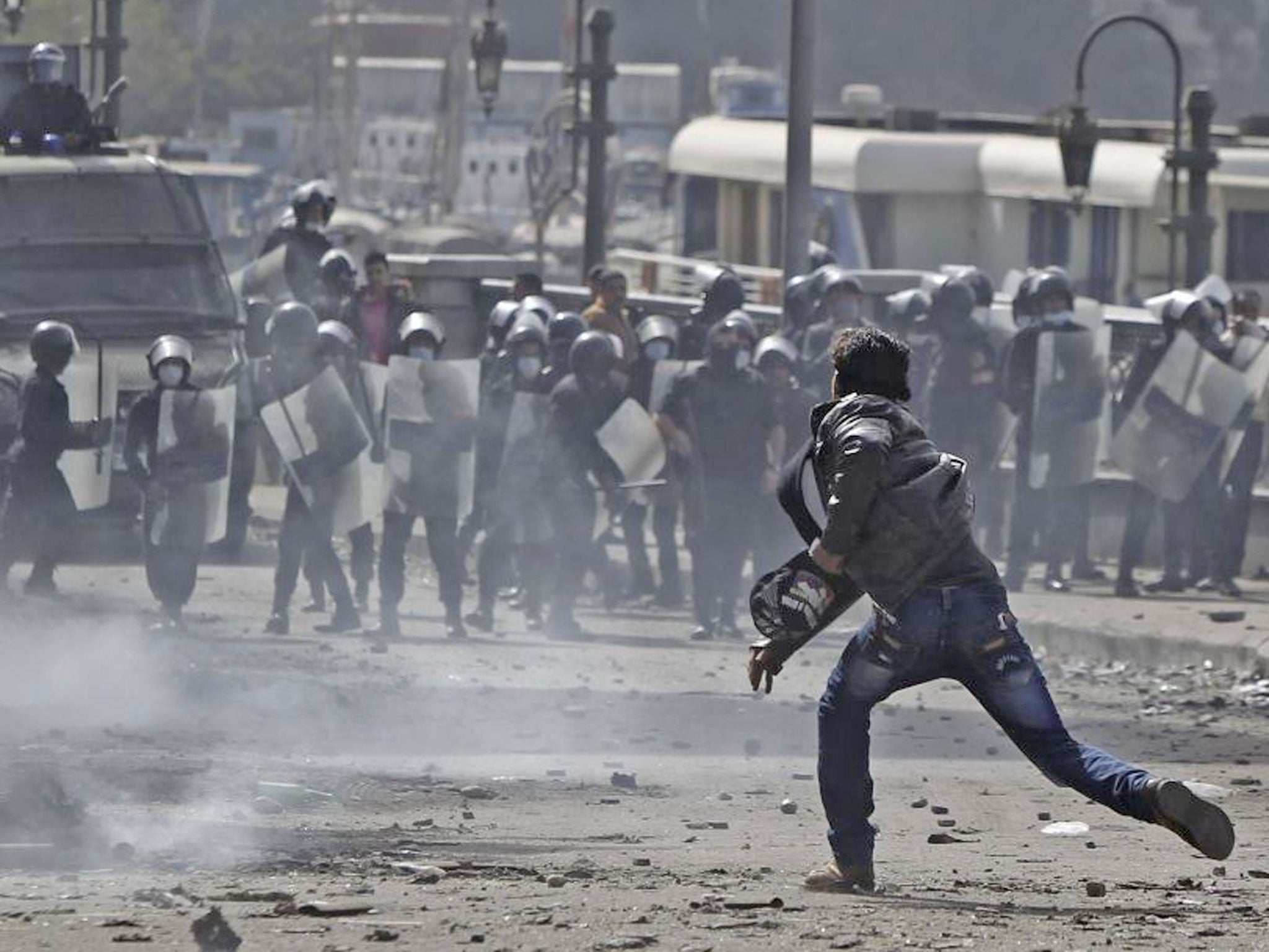 A protester opposing Egyptian President Morsi throws stone at riot police during clashes
