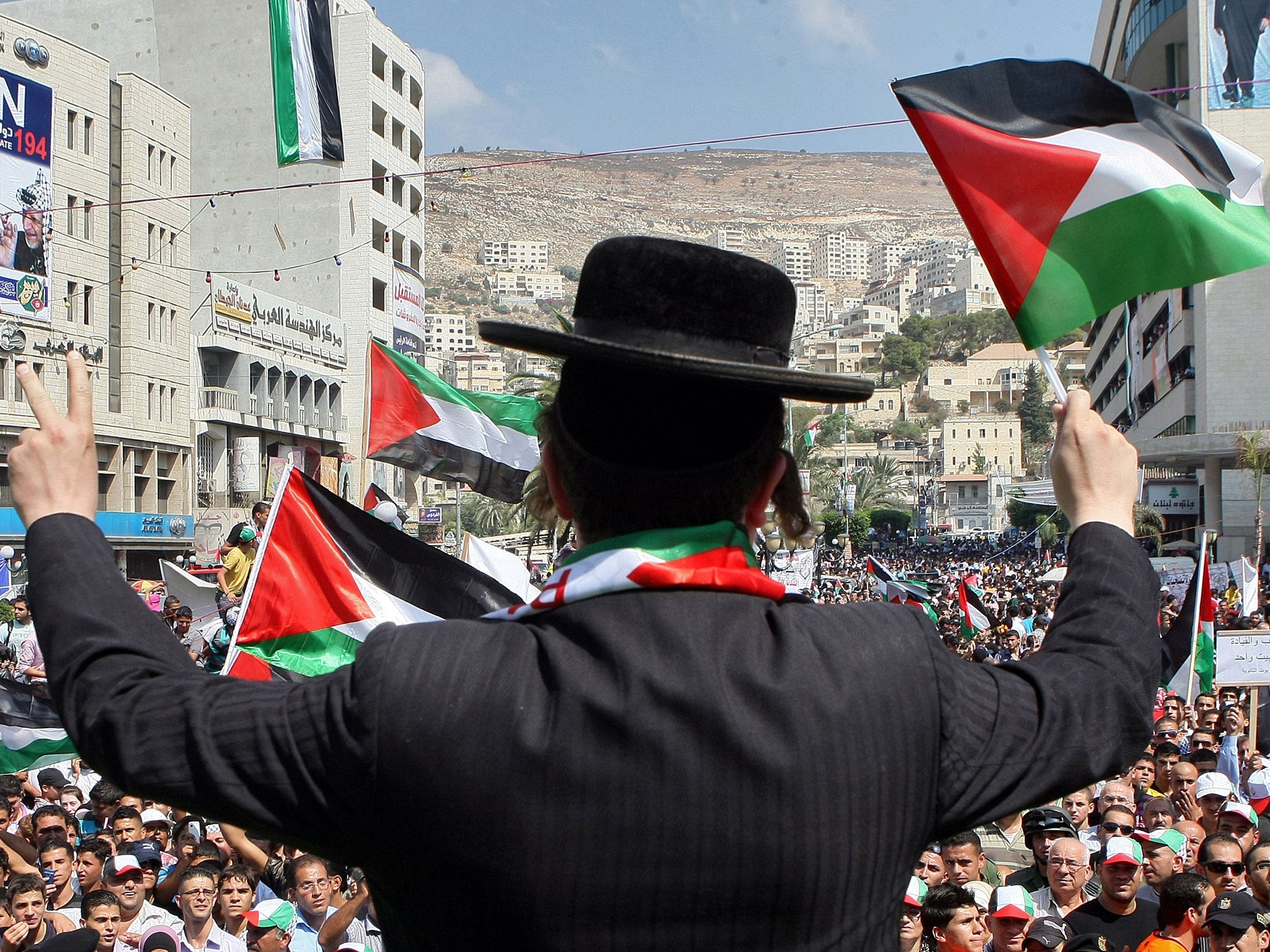 A member of Neturei Karta, a small faction of ultra-Orthodox Jews who oppose Israel's existence, wave a Palestinian flag to express support for the Palestinian bid for statehood recognition at the UN as thousands of Palestinians attend a demonstration on September 21, 2011 in the West Bank city of Nablus.