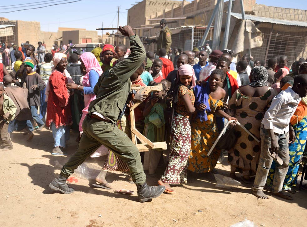 A Malian soldier trys to disperse looters in the streets of Timbuktu