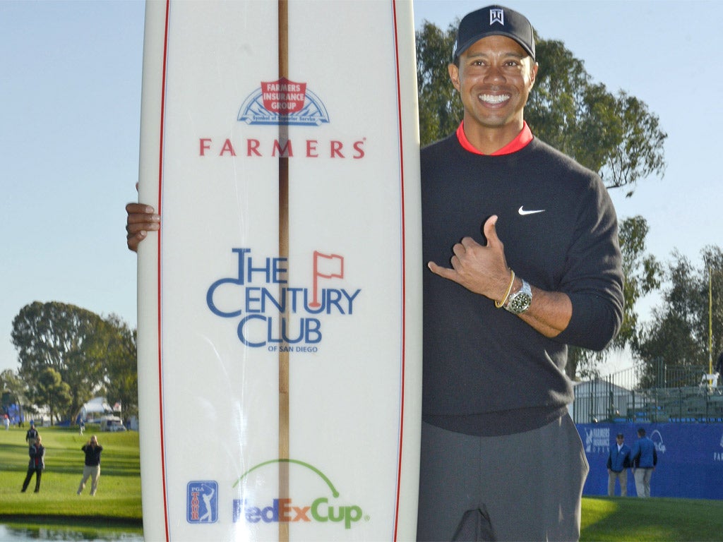 Tiger Woods poses with the winner’s traditional surfboard