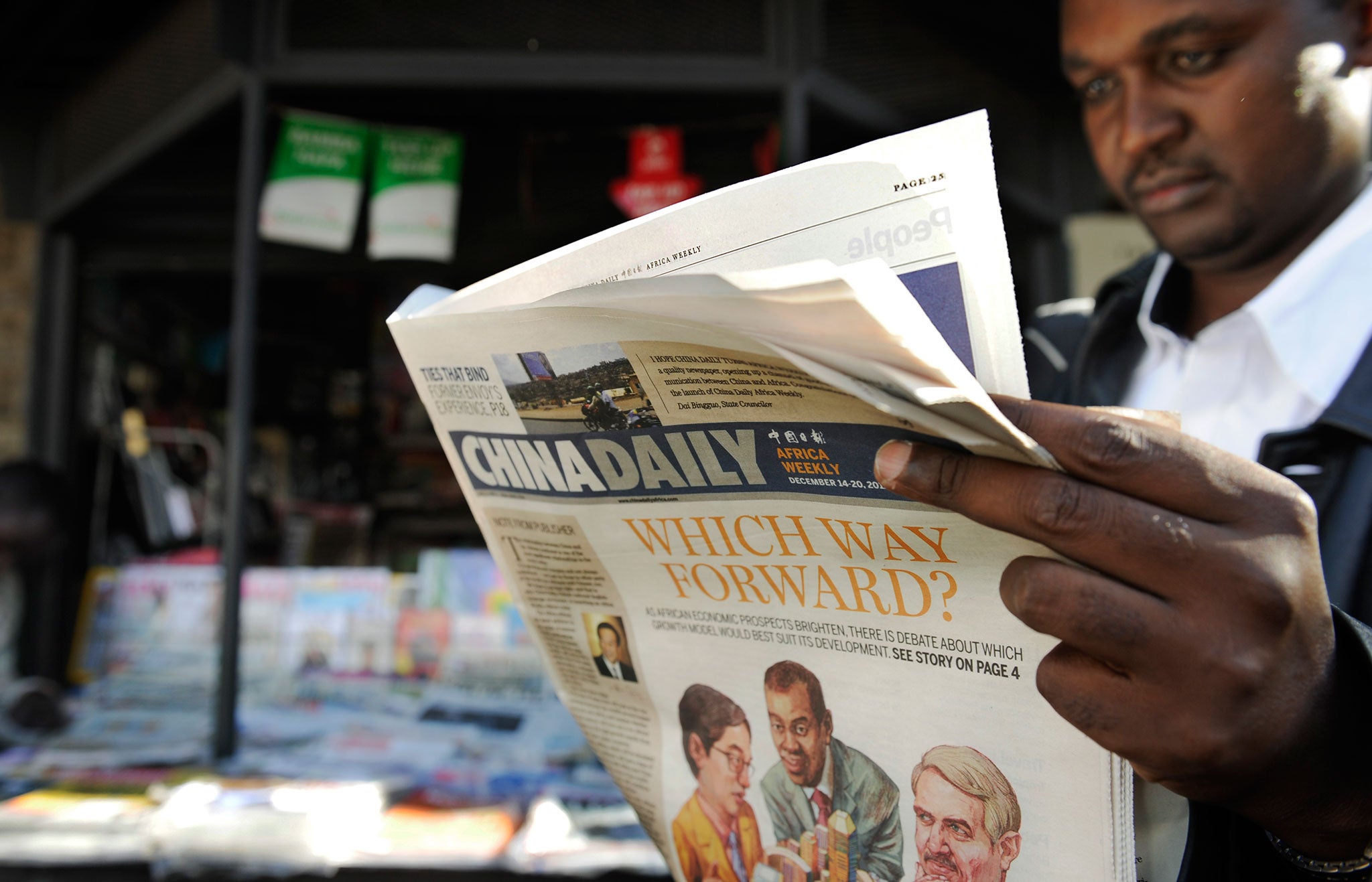 A newspaper consumer reads a copy of China's Africa edition of its daily newspaper infront of a news stand in the Kenyan capital