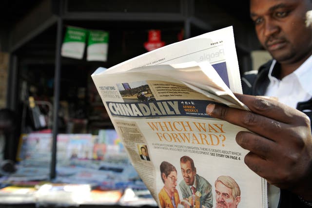A newspaper consumer reads a copy of China's Africa edition of its daily newspaper infront of a news stand in the Kenyan capital